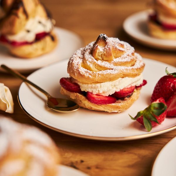 A closeup shot of delicious cream puff with strawberries on a wooden table